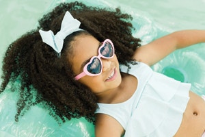 little girl wearing shades while wading in the pool